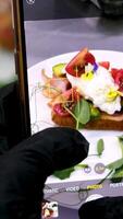 Blogger prepares eggs Benedict Man making vertical , stories, photo for social media of delicious restaurant food on smartphone. Male influencer shoot clip, film, reels on phone camera video