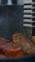 Cooking salmon steak grilling fillet salmon with asparagus, tomato, lemon. A chef's hand is squeezing a fresh lemon over a peace of red sea fish. Cooking process. Slow motion. close up video