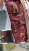 Beef tenderloin. Raw beef steak cut Chef sharpening his knife in front of kitchen table. Cooker preparing his tools before cutting raw pieceof meat and various vegetables 4k footage video