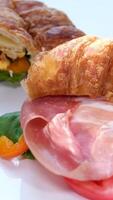 Zoom-in close up view of breakfast meal. croissant sandwich with bacon and scrambled eggs. Original tasty meal with meat served at Bali cafeteria in morning time video