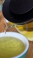 Pour herbal tea Pouring tea with orange, lemon and lime out of transparent tea pot into glass with nint.Brewing tea with honey and pancakes in background. Slow motion tea. video