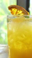 Rainbow paradise cocktail with a orange slice and a straw on a rustic white washed table on a tropical beach. Turquoise sea in the background video