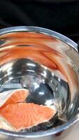 Freshly cut, oiled and marinated salmon in a black pan on a 360 degree rotating showcase. Healthy food Fresh Salmon Red Fish for Steak. 4k. Close-up slow-motion of sliced fresh raw red salmon. video