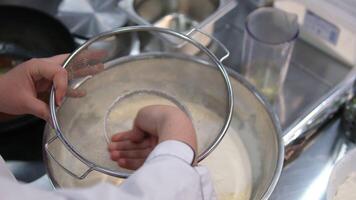 add flour through a sieve into the dough Extreme close up of woman s hand sifting flour through a small sieve adding it with a spoon. Handheld real time close up shot video