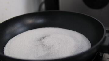 sugar in a frying pan melts in a pan on gas fire and turns into caramel by stirring with a wooden spoon video