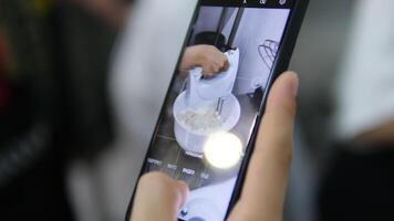 filming a mixer whipping cream on a mobile phone. baker's blog. blogger whips with a mixer video