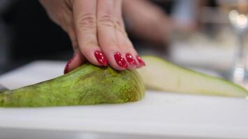 female hands cutting a pear and put it into a bowl with a knife. Hands puts the sliced pear in a bowl. Tasty sweet fruit. Hands chopping a pear on cutting board video