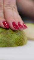 female hands cutting a pear and put it into a bowl with a knife. Hands puts the sliced pear in a bowl. Tasty sweet fruit. Hands chopping a pear on cutting board video