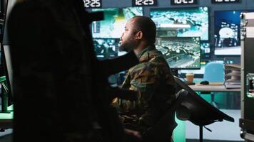 Army expert working in governmental facility operating surveillance tech, evaluating target data. Soldier doing job in HQ base of operations, engage enemy forces, camera A video