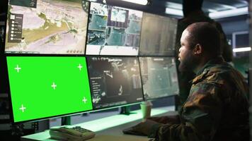 Military agent working in control room, using software on green screen devices, analyzing aerial reconnaissance data. Intelligence corps expert controlling drones with chroma key systems, camera B video