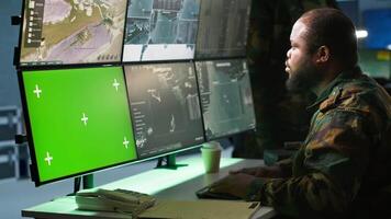Military agent working in control room, using software on green screen devices, analyzing aerial reconnaissance data. Intelligence corps expert controlling drones with chroma key systems, camera A video