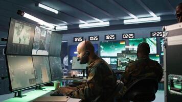 Army telecommunication systems operator using radio and satellite equipment. Middle Eastern military dispatcher managing communications networks, looking at screens, camera B video