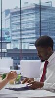 Vertical New employee signing his work contract after successful job interview with the HR staff, businesswomen shaking hands and welcoming man to the team. Job applicant securing a position. Camera B. video