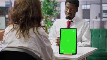 Job applicant and employer discussing in an interview with isolated mockup display on a device, high end corporate office. Businessman and HR recruiter share career development ideas. Camera A. video