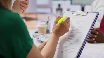 HR staff and applicant discussing the employment contract terms during the interview, providing explanations and clarifications. Job candidate reading the work agreement in high end office. Camera A. video