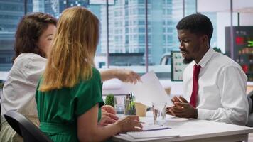 Job seeker at interview writing his name on application form, registering in the company database. Applicant filling in documents while he discusses career development plans. Camera A. video