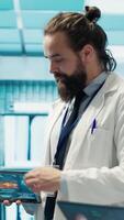 Vertical Doctors meet to discuss healthcare records and x ray scans results at treatment center. Licensed medics focus on tests for disease prevention, demonstrating teamwork and expertise. Camera A. video