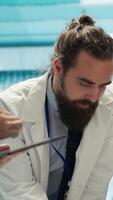 verticale soins de santé équipe examine tester résultats pour potentiel dangereux diagnostic, à la recherche à radiographie scanne pendant réunion. médecins avec compétence dans radiologie travail sur maladie la prévention. caméra un. video