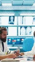 Vertical Radiologists and doctors analyze x rays and discuss patient care in a medical office. Team of healthcare specialists working together to provide accurate diagnosis and treatment plans. Camera B. video
