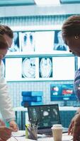 Vertical Team of specialists reviewing ecg results in a meeting at a private clinic, analyzing cardiovascular system on a radiography for disease prevention. Consulting scans and records. Camera B. video