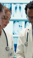 Vertical Specialists discuss x ray results and patient care strategy in a medical office. Team of licensed doctors working together to provide accurate diagnosis and effective treatment plans. Camera A. video