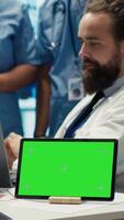 Vertical Diverse team of medics analyze x rays next to mockup copy space and discuss treatment plans in a medical office. Healthcare specialists working to provide diagnosis on insurance. Camera A. video