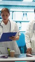 Vertical Expert physicians comparing test results and healthcare records in cabinet, consulting colleagues for disease prevention. Diverse medics sharing their professional expertise in a meeting. Camera B. video