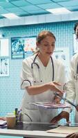 Vertical Group of healthcare workers analyzing diagnostic data and planning treatment in a private clinic, emphasizing collaboration. Coordinating recovery plans after recent test results. Camera B. video