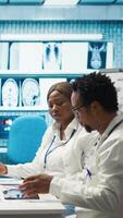 Vertical Healthcare experts in a meeting discussing treatment protocols and improvements. Doctors and nurses evaluating diagnostic results in a private clinic to enhance medical services quality. Camera B. video