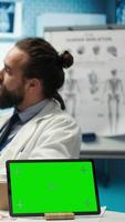 Vertical Licensed doctor and his staff review x ray scan results next to isolated copy space screen, examining hospital records before putting a diagnosis. Consulting analytics and radiography. Camera B. video