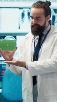 Vertical Medic presenting a box with isolated mockup screen during a meeting for disease prevention, conducting analytics and control of x ray scans results in a facility. Radiology department. Camera A. video