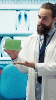 Vertical Medical expert showing a box with green screen during a meeting for diagnosis and disease prevention, conducting a detailed evaluation of x ray scans and lab test results in a clinic. Camera A. video