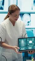 Vertical Diverse medical team examining test results and discussing innovative treatment plans at a modern clinic to enhance patient care quality. Doctors and nurses review x ray scans. Camera A. video