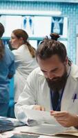 Vertical Diverse team of medics applauding expert physician after finding a diagnosis for a dangerous illness in cabinet. Happy competent doctors celebrating their healthcare service success. Camera B. video