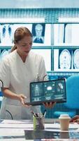 Vertical Diverse medical team examining test results and discussing innovative treatment plans at a modern clinic to enhance patient care quality. Doctors and nurses review x ray scans. Camera B. video