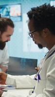 Vertical Medical experts analyze radiography scans in a meeting with the staff, working to develop new treatment options. Doing teamwork for analytics and diagnostics control, healthcare solutions. Camera B. video