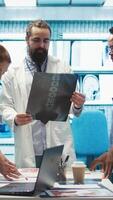 Vertical Radiologists and osteopaths review x ray results and discuss treatment plans. Team of licensed diverse experts working in a private clinic to provide comprehensive medical services. Camera B. video