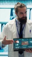Vertical Professional medic analyzing mri brain scan with his staff in medical office, neuroscientist examining tomography with diverse doctors. Experts in neuroscience at treatment center. Camera A. video