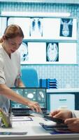 Vertical Team of doctors review electrocardiogram test results at a private facility, analyzing human organs on a radiography for disease prevention. Consulting hospital records and cardiology scan. Camera B. video