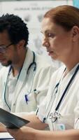 Vertical Medical expert reviews x ray results and discusses disease prevention during a meeting with healthcare staff, treatment options. Radiology doctors analyzing scans for diagnostic. Camera A. video