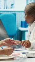 Vertical Radiologists and specialists examine x rays and discuss medical care in a private clinic. Team of healthcare experts working together to provide accurate diagnosis and treatment options. Camera A. video