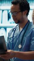 Vertical Physicians and radiologists analyzing x ray scans to create an effective treatment plan. Medics doing teamwork at a private clinic to ensure radiography based diagnostics for healthcare. Camera A. video