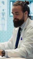 Vertical Tired worried doctor working after hours to find the diagnostic for a patient, feeling very stressed and trying to examine x ray results in medical cabinet. Frustrated overworked medic. Camera A. video