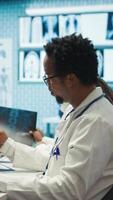 Vertical Physicians examining x ray scan results in a meeting with the staff, working to develop treatment plans. Doctors doing collective work for diagnostics control, healthcare industry. Camera B. video
