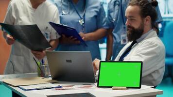 Diverse team of medics analyze x rays next to mockup copy space and discuss treatment plans in a medical office. Healthcare specialists working to provide diagnosis on insurance. Camera A. video