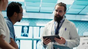 Neurology specialist examines magnetic resonance imaging brain scan with team during a meeting, looking at tomography for accurate neuroscience diagnosis. Diverse team of doctors. Camera A. video