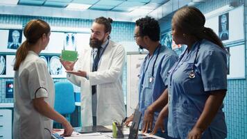Medic presenting a box with isolated mockup screen during a meeting for disease prevention, conducting analytics and control of x ray scans results in a facility. Radiology department. Camera B. video