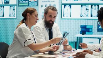 Healthcare experts in a meeting discussing treatment protocols and improvements. Doctors and nurses evaluating diagnostic results in a private clinic to enhance medical services quality. Camera A. video