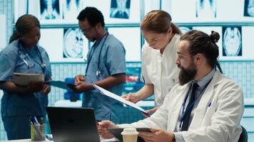 Healthcare experts in a treatment center analyzing x ray scans and test results in a meeting, collaborating on diagnostics and treatment plans for disease prevention. Collective work. Camera A. video