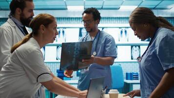 Physicians and radiologists analyzing x ray scans to create an effective treatment plan. Medics doing teamwork at a private clinic to ensure radiography based diagnostics for healthcare. Camera B. video
